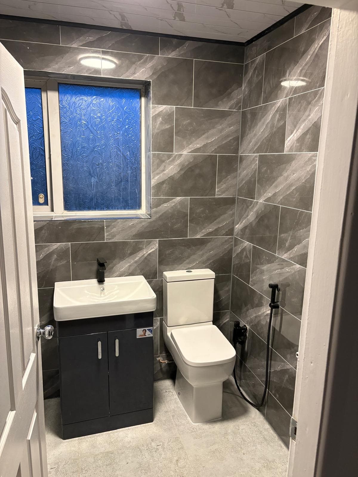 Fitted bathroom with vanity unit, toilet and grey marble-effect tiling in Birmingham