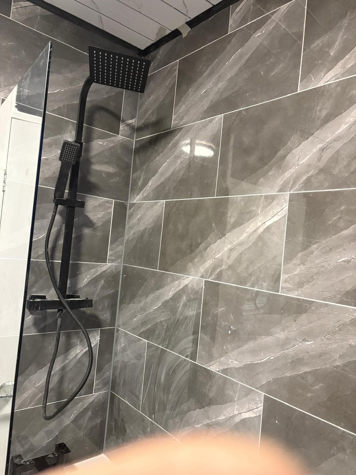 Black rainfall shower and grey marble-effect tiling fitted by CH Developments in Birmingham